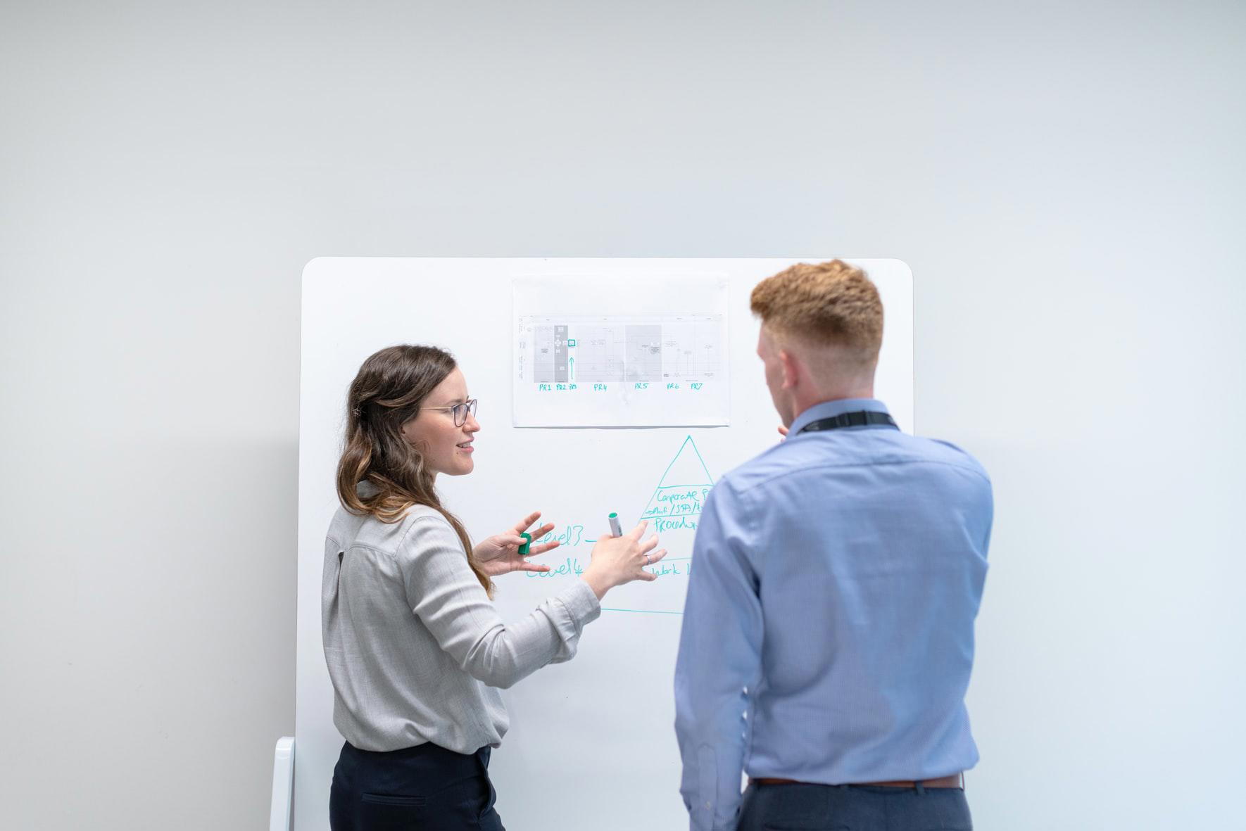 two people having a discussion near a whiteboard