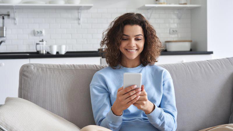 person looking at smartphone on sofa
