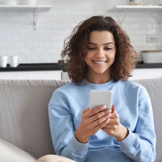 person looking at smartphone on sofa