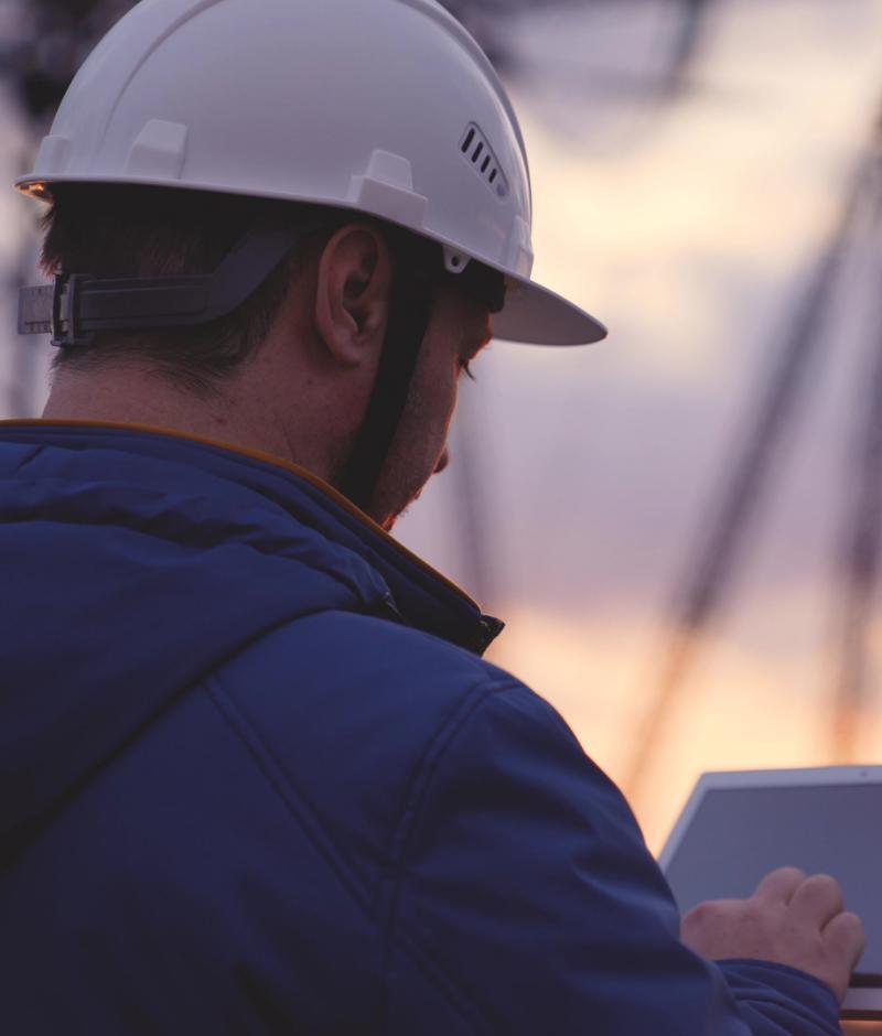 person in hard hat using a laptop