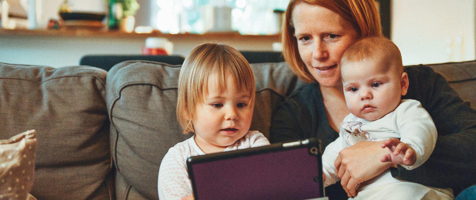 A mother with two young children viewing story videos of her partner on deployment