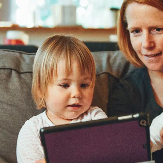A mother with two young children viewing story videos of her partner on deployment